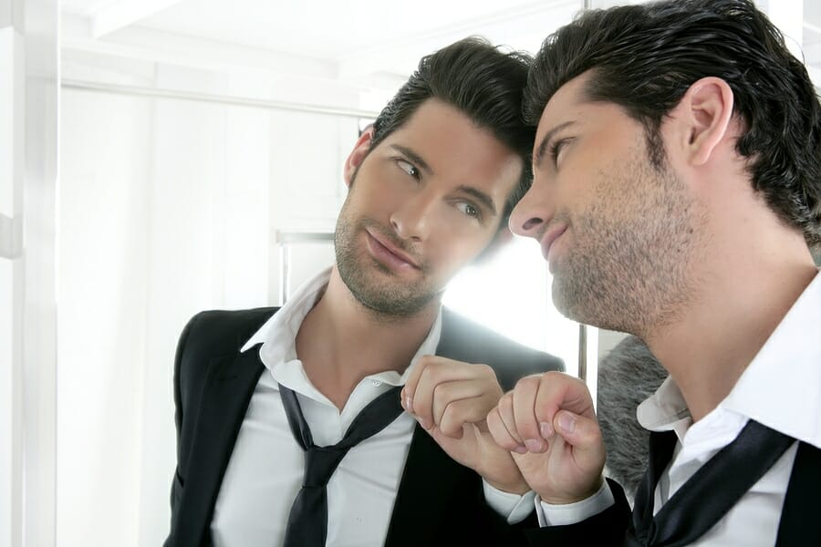 Handsome narcissistic young man looking in a mirror